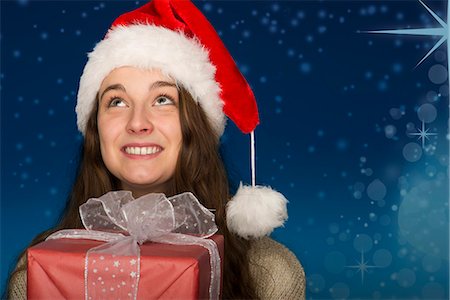 female holding christmas present - Young woman wearing Santa hat, holding Christmas present, portrait Stock Photo - Premium Royalty-Free, Code: 632-06118192