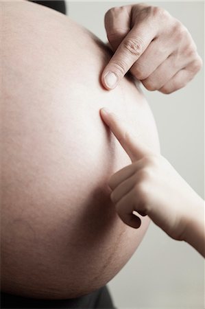 showing belly - Child's hand touching pregnant woman's belly Stock Photo - Premium Royalty-Free, Code: 632-06118318