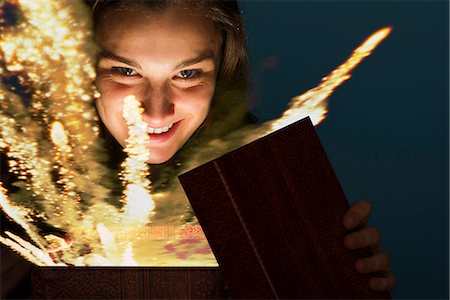 Young woman opening gift box containing glowing fireworks Stock Photo - Premium Royalty-Free, Code: 632-06118311