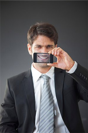 Man holding up smartphone displaying image of his own smile Foto de stock - Royalty Free Premium, Número: 632-06118442