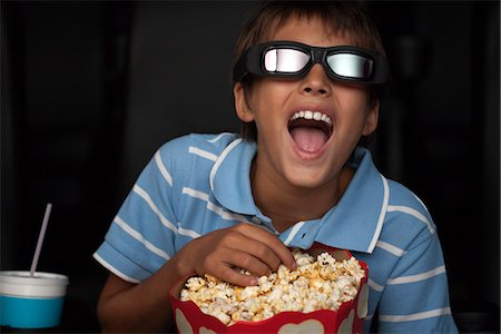 popcorn in the theatre - Boy laughing and eating popcorn during 3-D movie in theater Stock Photo - Premium Royalty-Free, Code: 632-06118453