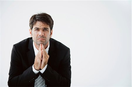 Businessman with hands clasped under chin, disappointed expression on face Stock Photo - Premium Royalty-Free, Code: 632-06118495