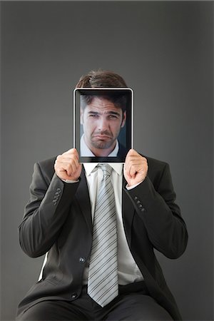 picture within picture - Man holding frowning photograph in front of his face Stock Photo - Premium Royalty-Free, Code: 632-06118531