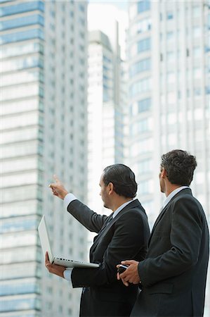 pointing - Businessmen using laptop computer outdoors, one man pointing into distance Stock Photo - Premium Royalty-Free, Code: 632-06118550