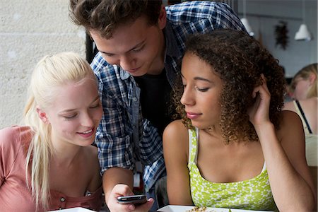 Friends looking at cell phone together Stock Photo - Premium Royalty-Free, Code: 632-06118639