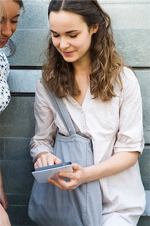 Young woman showing digital tablet to friend Stock Photo - Premium Royalty-Free, Code: 632-06118714