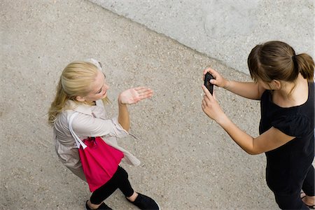 Young woman photographing friend with cell phone, elevated view Foto de stock - Sin royalties Premium, Código: 632-06118736