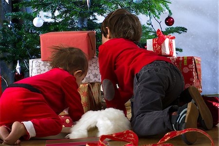 simsearch:632-06354083,k - Young siblings kneeling before Christmas tree, opening presents, rear view Fotografie stock - Premium Royalty-Free, Codice: 632-06118768
