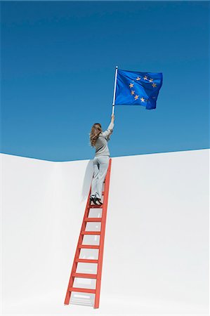 Businesswoman standing at top of ladder, holding European Union flag Stock Photo - Premium Royalty-Free, Code: 632-06118845