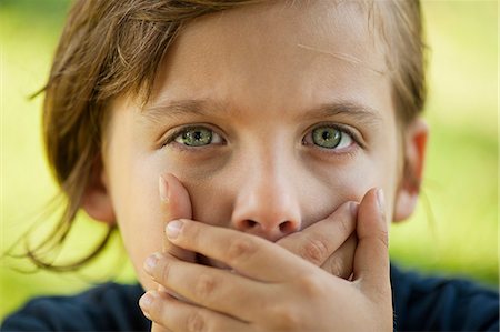 Boy covering mouth with hands Fotografie stock - Premium Royalty-Free, Codice: 632-06118874