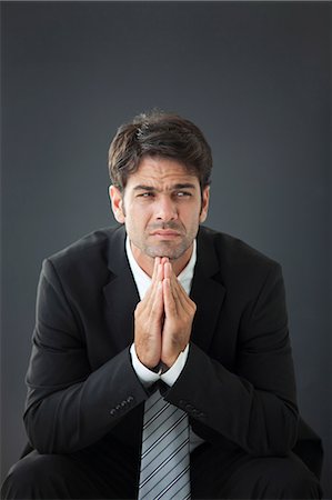 simsearch:632-06118531,k - Businessman with hands clasped under chin, displeased expression on face Stock Photo - Premium Royalty-Free, Code: 632-06118944