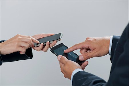 Colleagues exchanging information with smartphones, cropped Stock Photo - Premium Royalty-Free, Code: 632-06317059