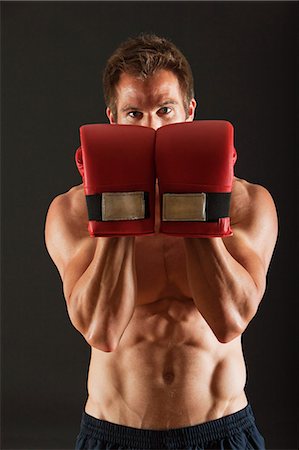 Barechested boxer holding up gloves in front of face in defensive position Stock Photo - Premium Royalty-Free, Code: 632-06317066