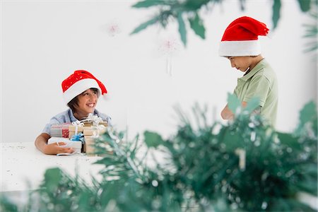 smiling and sulking - Boy holding armful of Christmas presents, smiling mischievously at sulky brother Stock Photo - Premium Royalty-Free, Code: 632-06317067