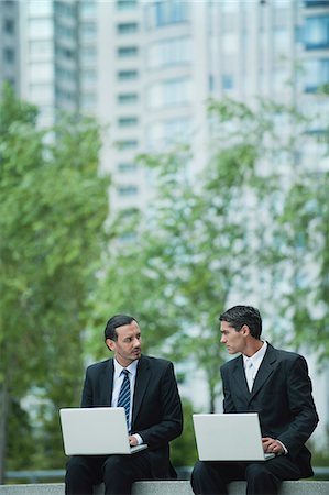 sitting on lap facing each other - Business associates sitting outdoors with laptop computers Stock Photo - Premium Royalty-Free, Code: 632-06317098