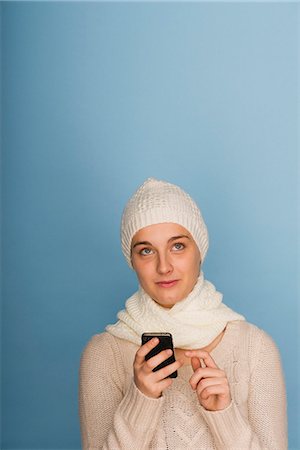 Young woman using cell phone, looking up in thought Stock Photo - Premium Royalty-Free, Code: 632-06317092