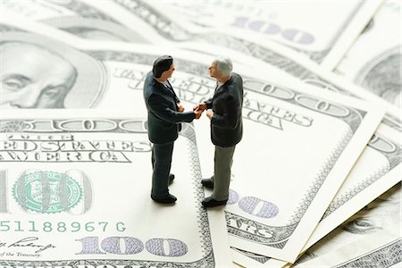 financial deal - Male figurines shaking hands on pile of one hundred dollar bills Stock Photo - Premium Royalty-Free, Code: 632-06317137