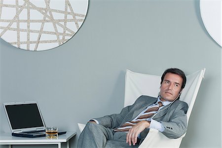 Mature businessman relaxing on chair with earphones Stock Photo - Premium Royalty-Free, Code: 632-06317178