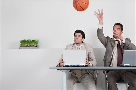 Young businessman watching colleague throwing basketball Stock Photo - Premium Royalty-Free, Code: 632-06317201