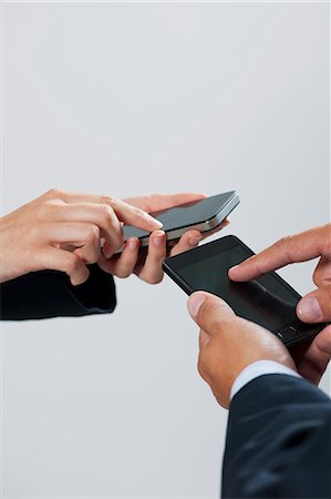 simsearch:632-06317171,k - Colleagues exchanging information with smartphones, cropped Stock Photo - Premium Royalty-Free, Code: 632-06317324