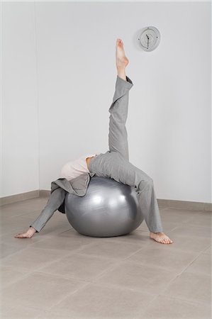 Businesswoman stretching on fitness ball in office Stock Photo - Premium Royalty-Free, Code: 632-06317409