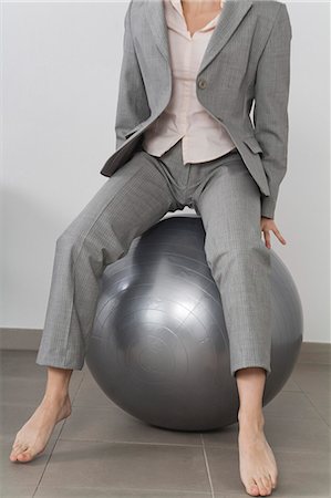 Businesswoman boucing on fitness ball, cropped Stock Photo - Premium Royalty-Free, Code: 632-06317426