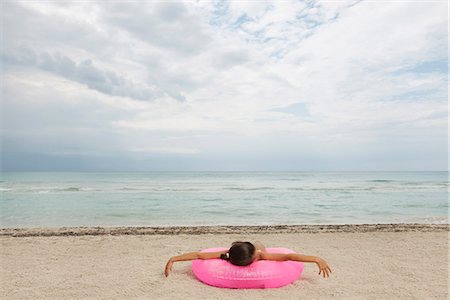 relaxing on innertube - Jeune fille allongée sur un anneau gonflable sur la plage, vue arrière Photographie de stock - Premium Libres de Droits, Code: 632-06317568