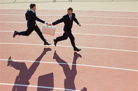 Businessmen passing briefcase while running on running track Stock Photo - Premium Royalty-Free, Code: 632-06317606