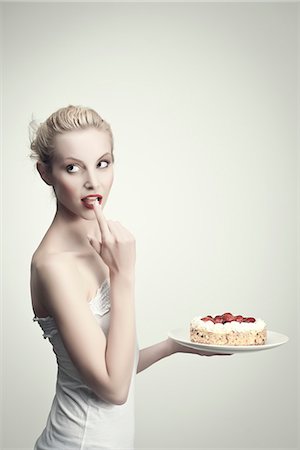 señuelo - Young woman holding strawberry cake, licking cream off finger, portrait Foto de stock - Sin royalties Premium, Código: 632-06317725