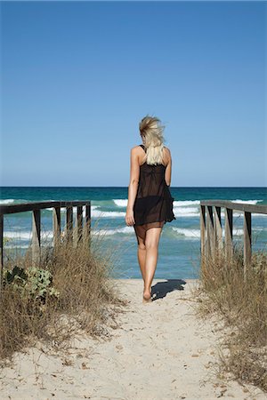 Woman walking on path toward sea, rear view Stock Photo - Premium Royalty-Free, Code: 632-06317782