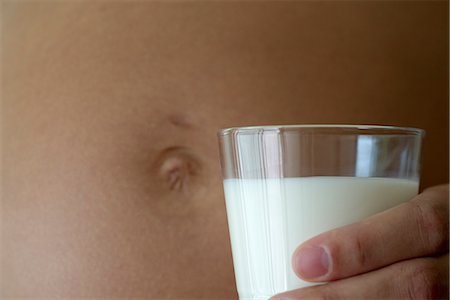 simsearch:632-06318000,k - Pregnant woman holding glass of milk beside stomach, cropped Fotografie stock - Premium Royalty-Free, Codice: 632-06317878