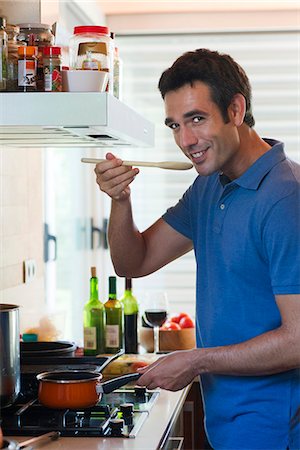 pan on stove - Man cooking in kitchen, smiling at camera Stock Photo - Premium Royalty-Free, Code: 632-06317925