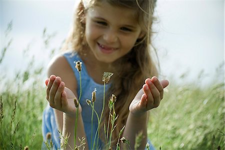 Girl staring at butterfly on wildflower Stock Photo - Premium Royalty-Free, Code: 632-06318011