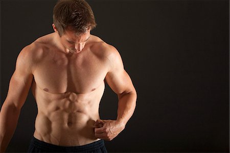 Barechested muscular man pinching waist Stock Photo - Premium Royalty-Free, Code: 632-06318033