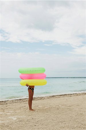 simsearch:649-06623087,k - Girl holding stack of inflatable rings on beach, face obscured Foto de stock - Royalty Free Premium, Número: 632-06318057