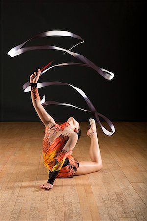 Gymnast bending backwards on floor, twirling ribbon Stock Photo - Premium Royalty-Free, Code: 632-06318101