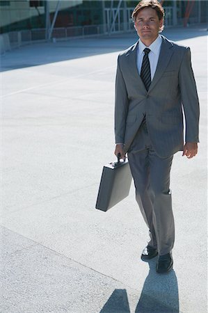 simsearch:632-05816428,k - Businessman walking outdoors with briefcase in hand Stock Photo - Premium Royalty-Free, Code: 632-06354044