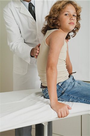 Boy sitting on examination table, doctor examining his back Stock Photo - Premium Royalty-Free, Code: 632-06354045