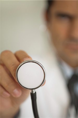 simsearch:632-06118662,k - Doctor holding stethoscope, focus on foreground Stock Photo - Premium Royalty-Free, Code: 632-06354137