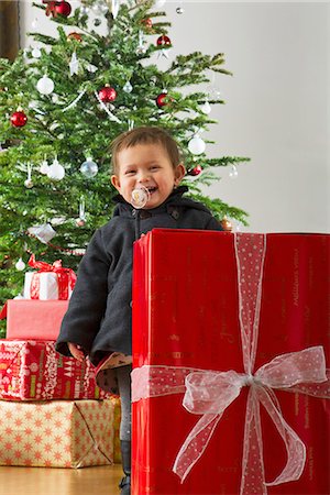 simsearch:632-06354055,k - Baby girl standing behind large Christmas present, laughing Foto de stock - Sin royalties Premium, Código: 632-06354228