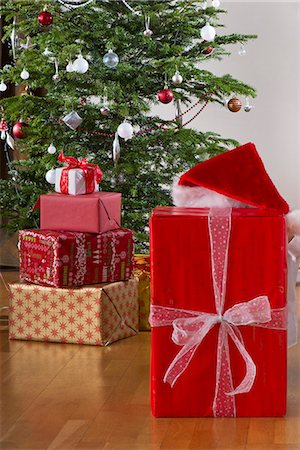 Person in Santa hat hiding behind Christmas present Foto de stock - Sin royalties Premium, Código: 632-06354280