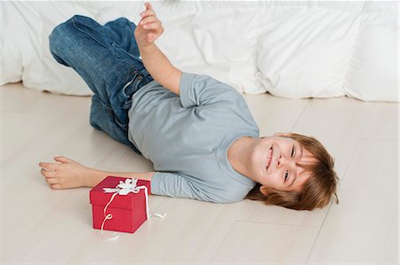 surprise boy - Boy lying on floor beside gift box Stock Photo - Premium Royalty-Free, Code: 632-06354283