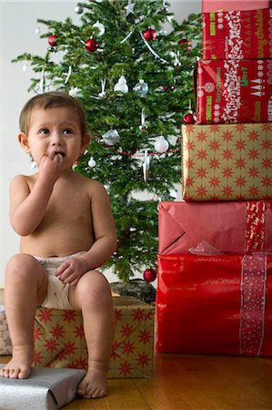 diaper kid pictures - Baby girl sitting on Christmas present, eating snack Foto de stock - Sin royalties Premium, Código: 632-06354301