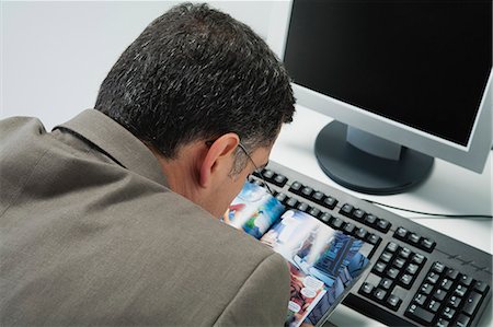 simsearch:632-07674665,k - Mature man reading comic book at desk in office, rear view Stock Photo - Premium Royalty-Free, Code: 632-06354340