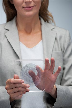 studio graphic - Femme d'affaires de manipuler la carte du monde sur une tablette numérique transparente Photographie de stock - Premium Libres de Droits, Code: 632-06354445