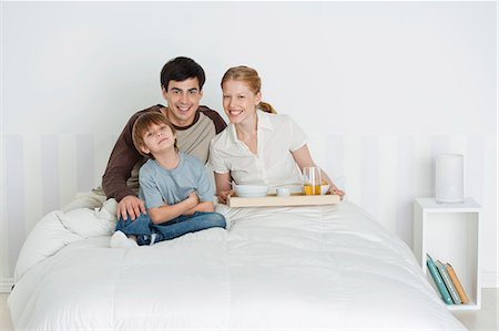 Young family sitting in bed, mother holding breakfast tray Stock Photo - Premium Royalty-Free, Code: 632-06353997