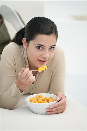 simsearch:632-06029430,k - Young woman lying on stomach, eating bowl of cereal Stock Photo - Premium Royalty-Free, Code: 632-06404275