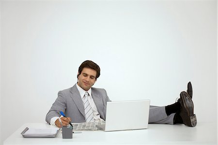 person being lazy on computer - Businessman sitting with feet on desk, looking at newspaper Stock Photo - Premium Royalty-Free, Code: 632-06404301