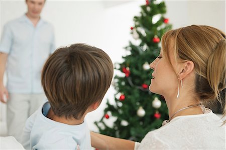 simsearch:6122-07707403,k - Mother and son sitting in front of Christmas tree, father standing in background Foto de stock - Sin royalties Premium, Código: 632-06404338
