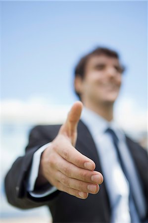 smile and greeting - Businessman extending hand for handshake, low angle view Stock Photo - Premium Royalty-Free, Code: 632-06779111